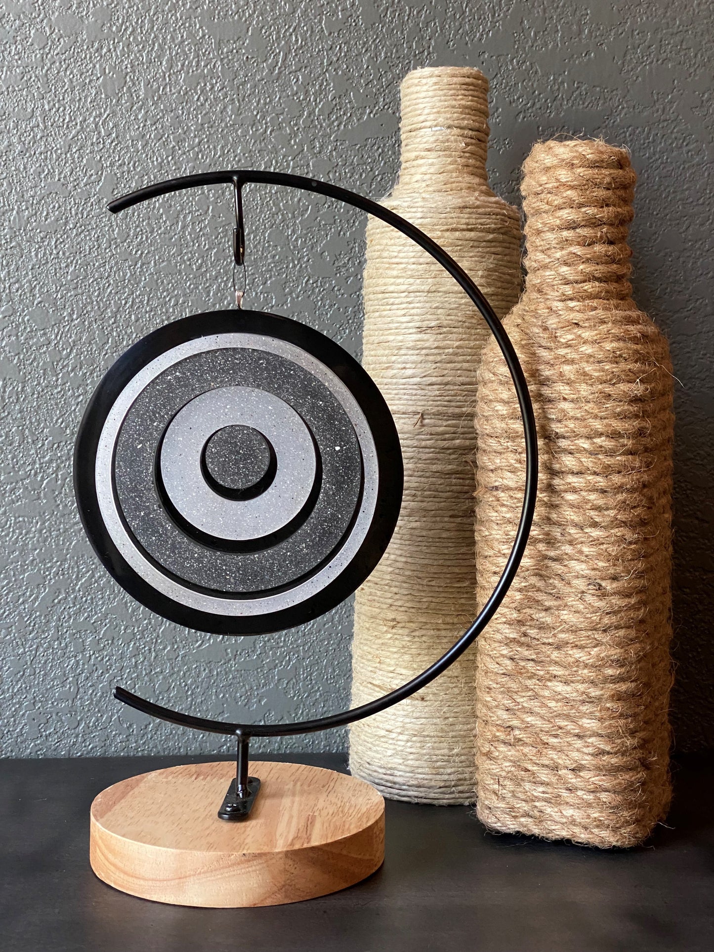 Decorative ash infused art with concentric circles and wooden elements on a gray background