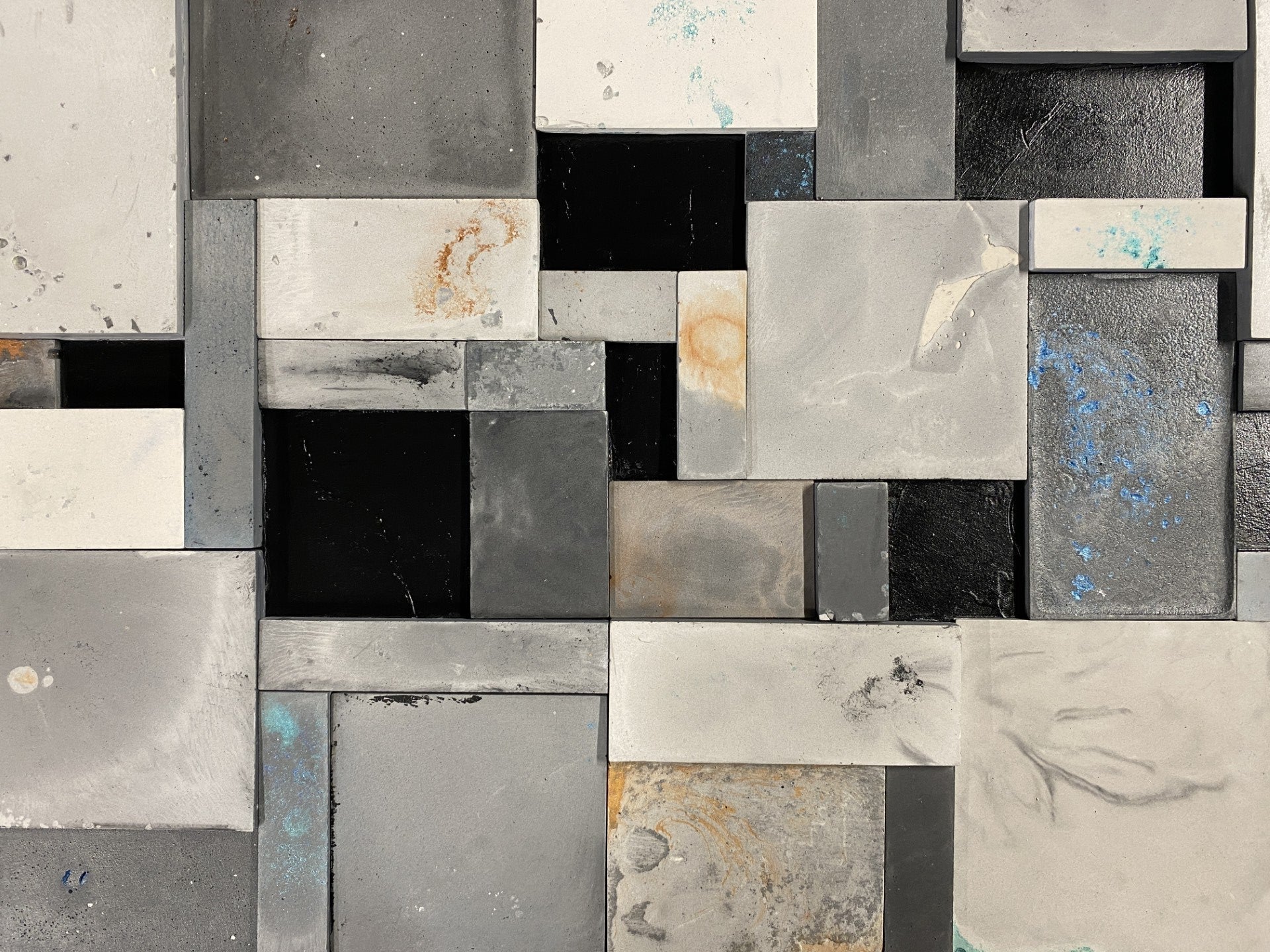 Mosaic pattern of variously shaped and sized metallic tiles in gray, black, and white.