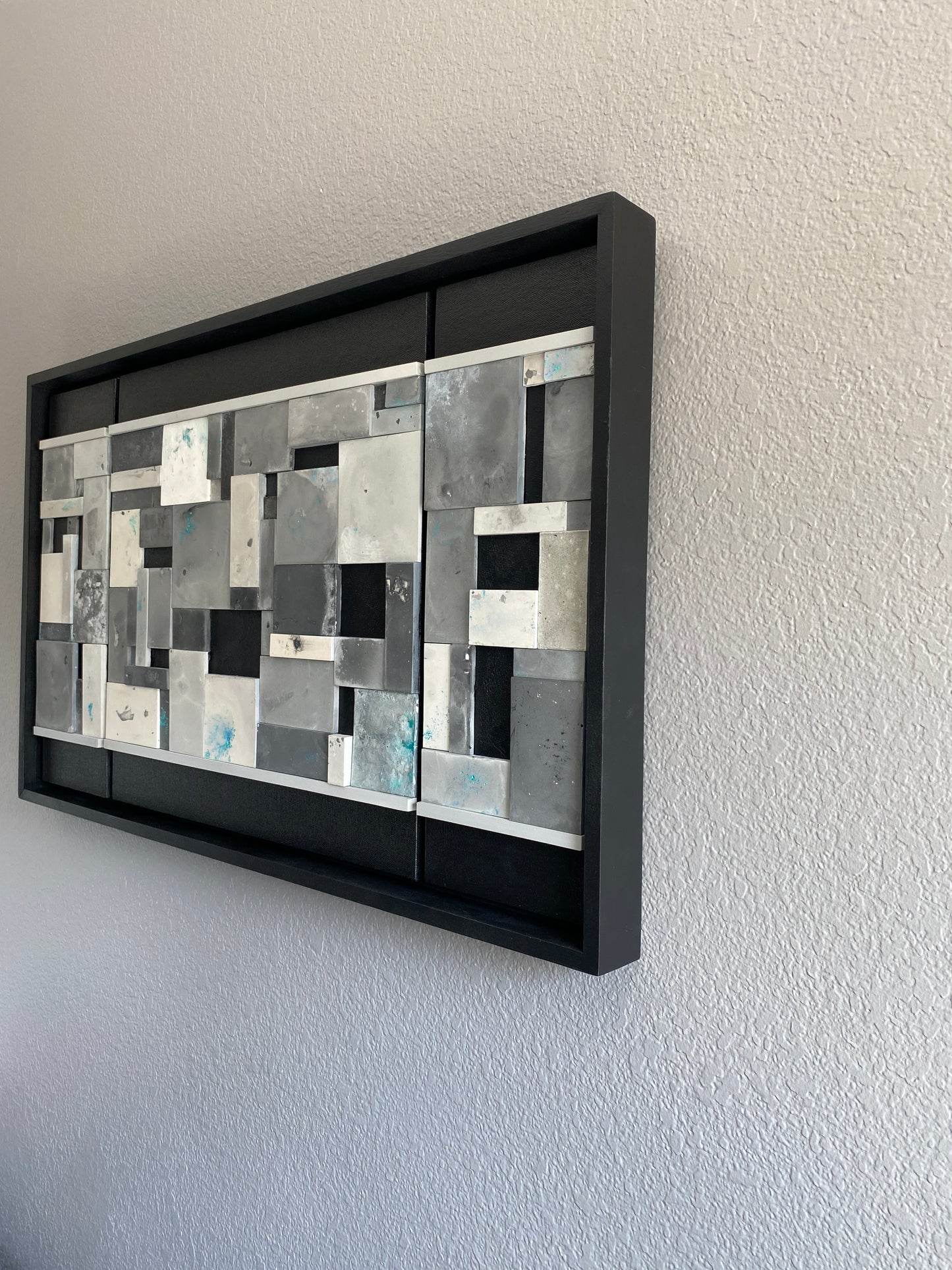 Side view of Ocean’s Memory from the left, showing depth, texture, and the subtle glow of the wood frame on grey wall.