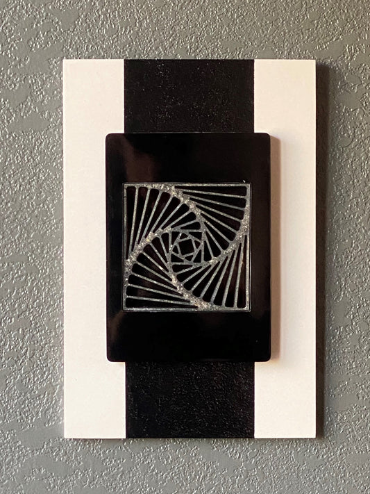 Pinwheel cremation ash memorial wall art with spiraling resin center on white frame and black border