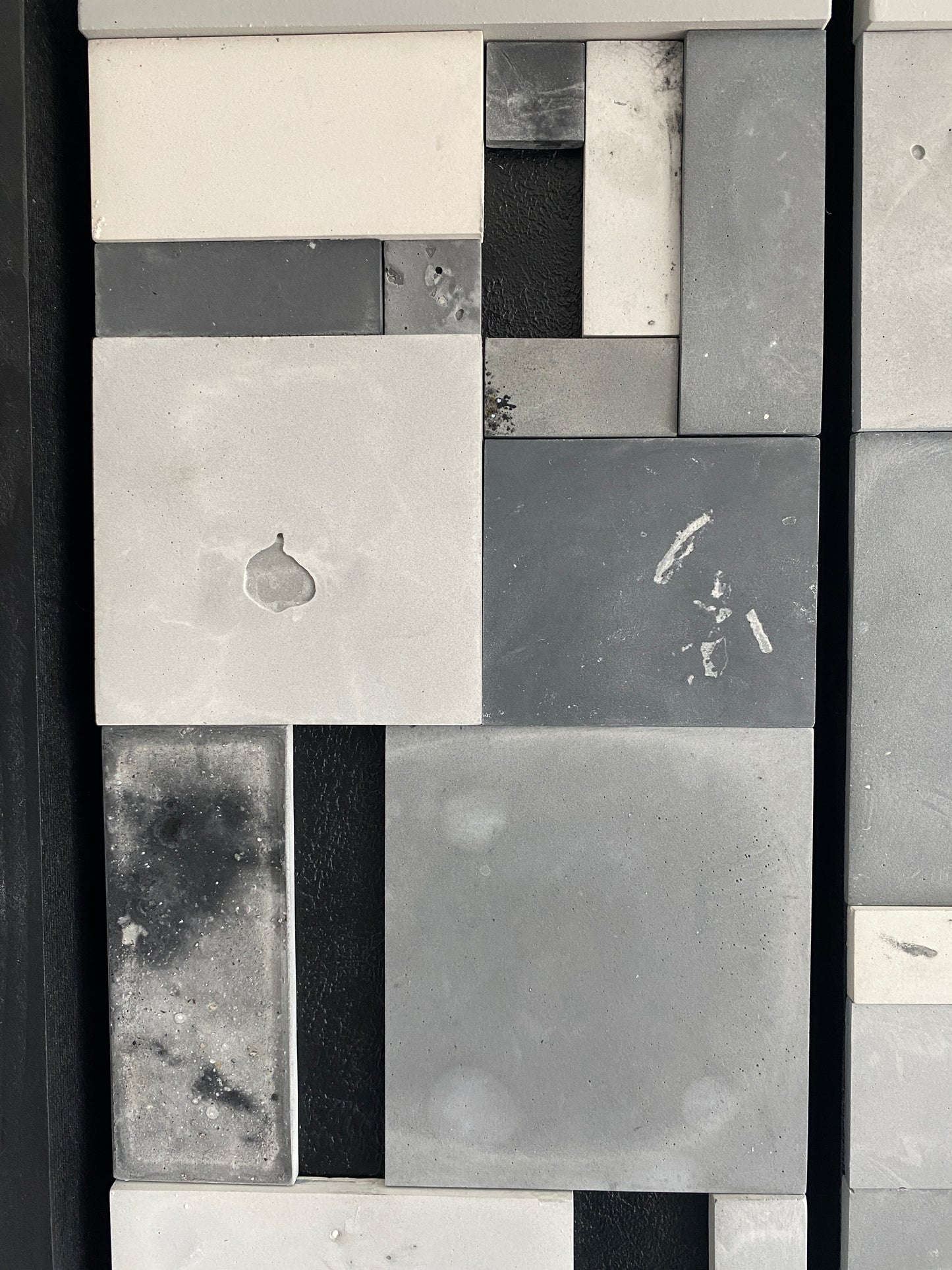 Pattern of gray, black, and white tiles on a wall.
