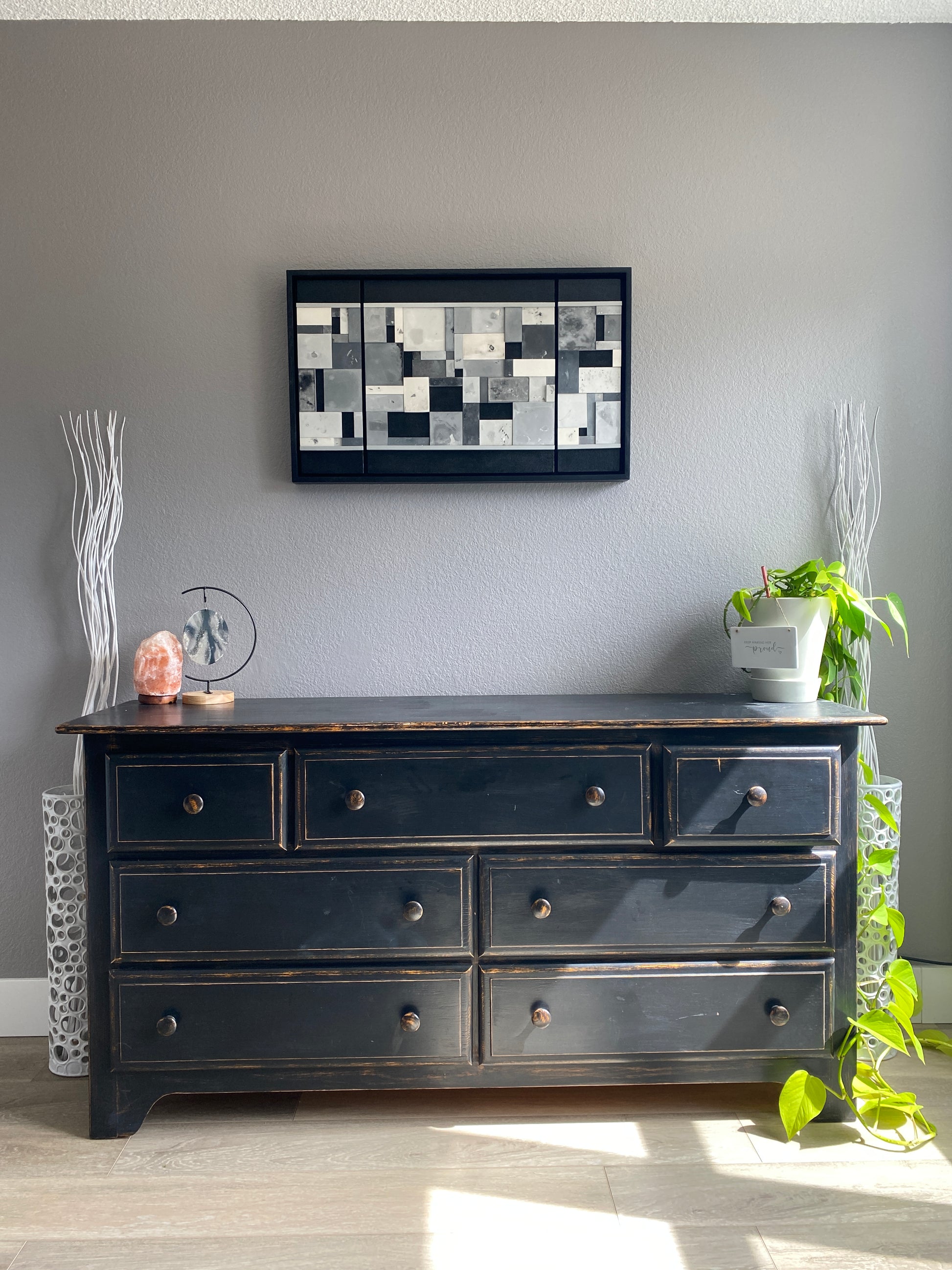 Black dresser  with decorative elements on a gray wall