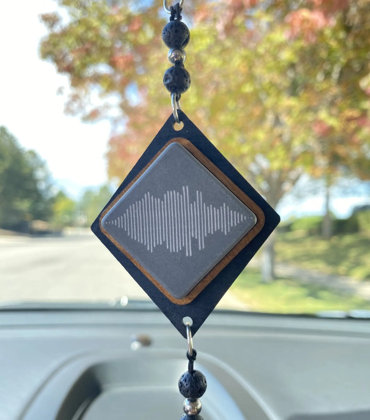 A diamond shaped car charm with an engraved phrase