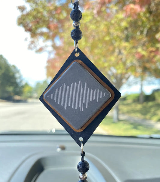 A diamond shaped car charm with an engraved phrase