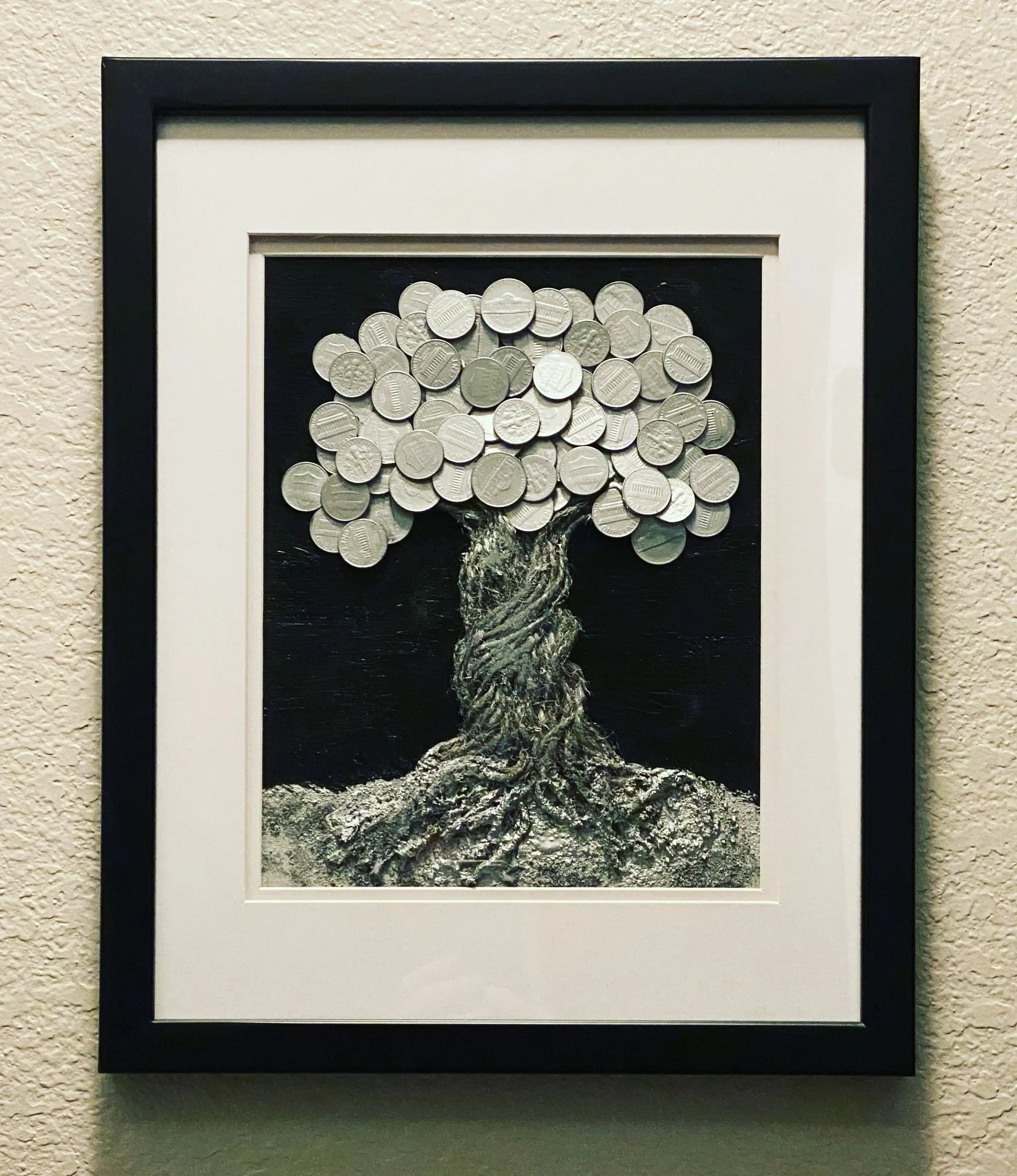 Framed mixed‑media artwork featuring a silver rope tree with coins made from money left in Ally’s wallet.