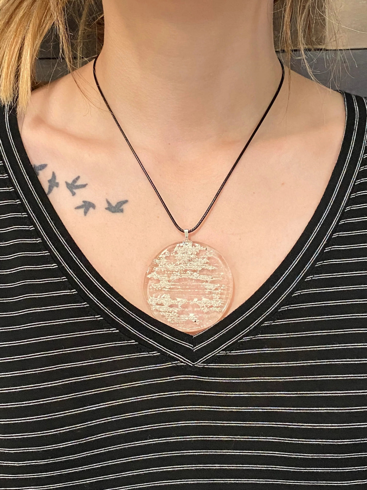 Close-up of a person wearing a black shirt, showing tattoos on the shoulder and chest.
