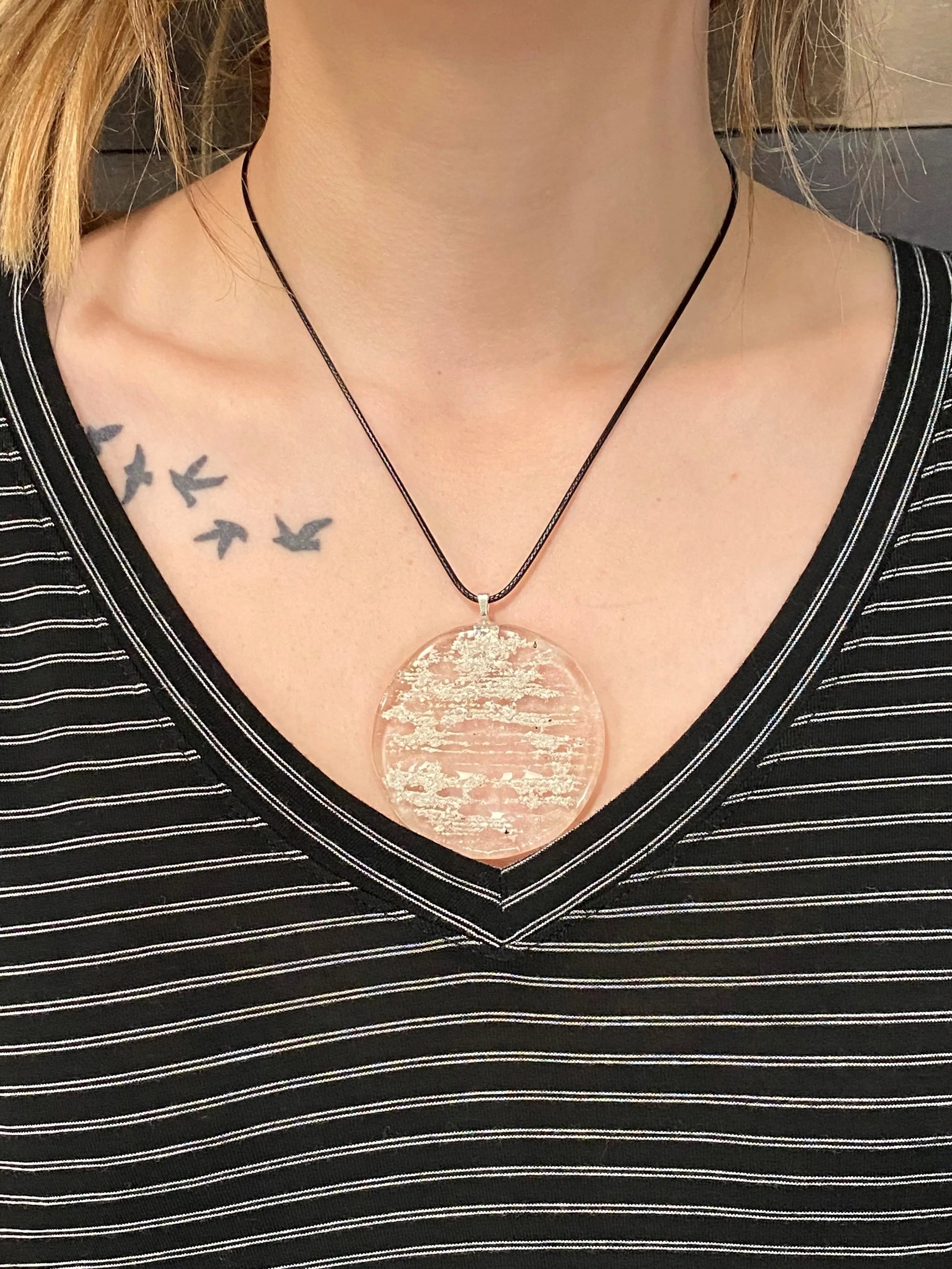 Close-up of a person wearing a black shirt, showing tattoos on the shoulder and chest.