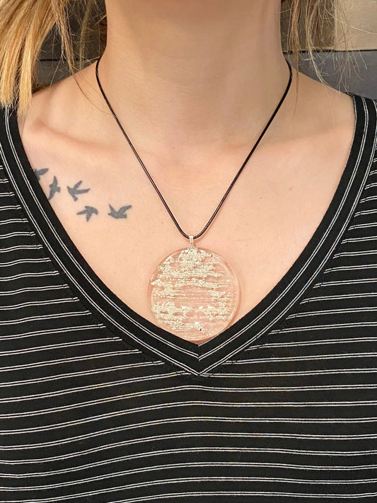 Close-up of a person wearing a black shirt, showing tattoos on the shoulder and chest.