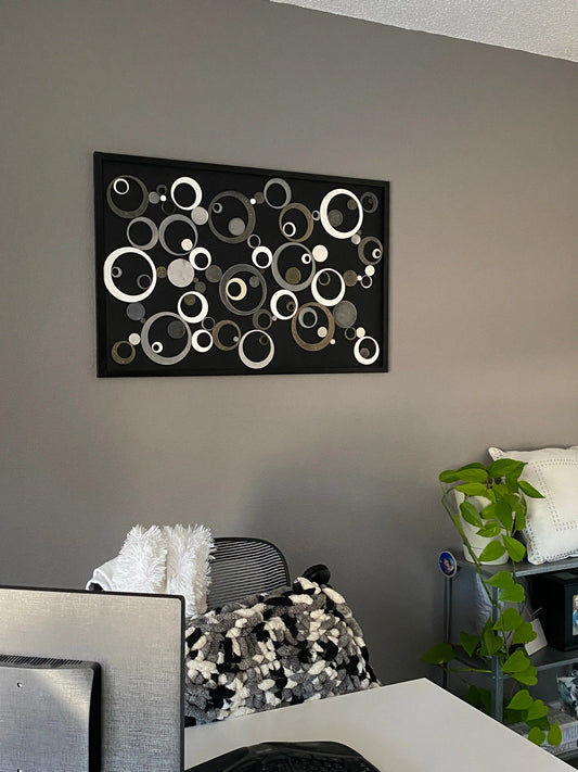 Mixed‑media artwork featuring resin circles of varying sizes arranged in a black wooden frame, with several circles infused with ashes.