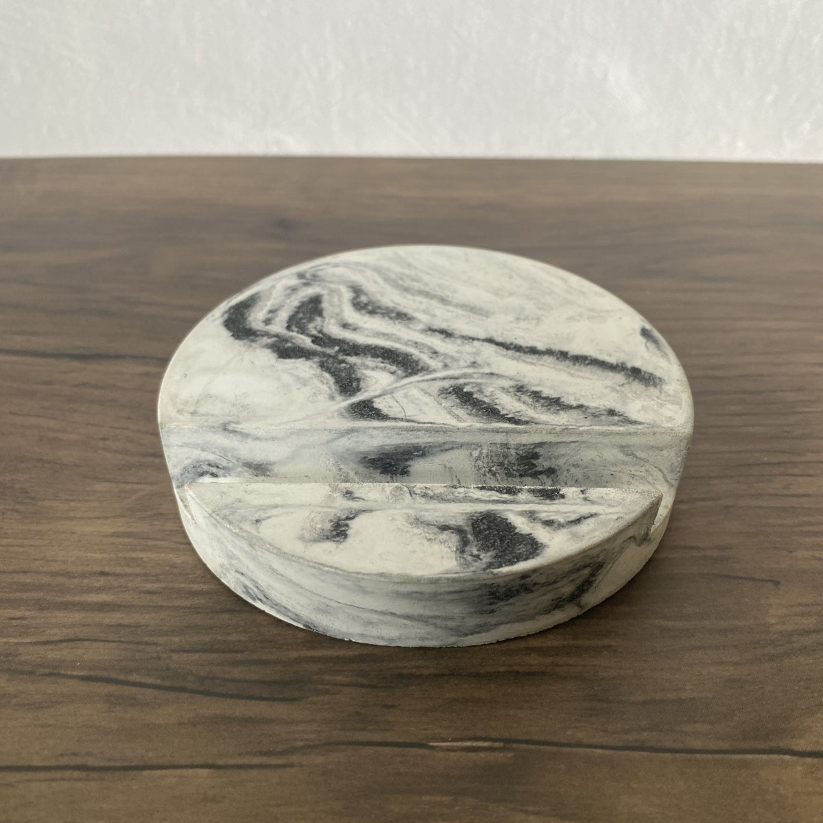 Black and white round marbled concrete stand sitting on brown table.