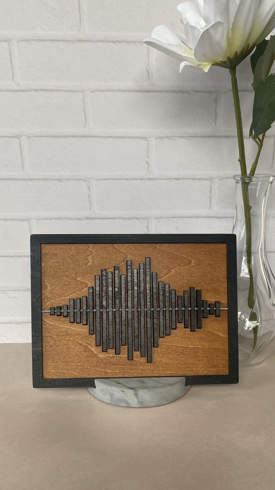 Black framed sound wave with warm tone stained wood and marbled stand.