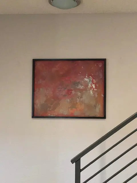 Abstract artwork with red, orange, and yellow spray paint on a metal sheet, framed in wood.