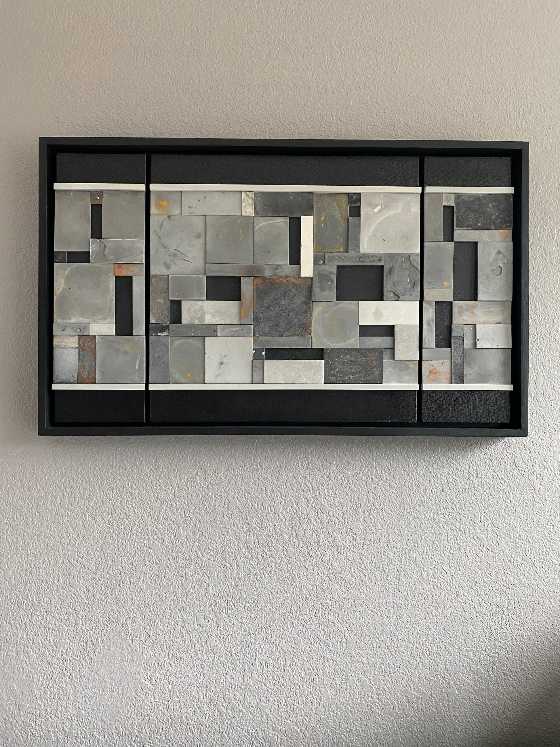 Full front view of mosaic wall art triptych with golds and bronze in black floating frame.