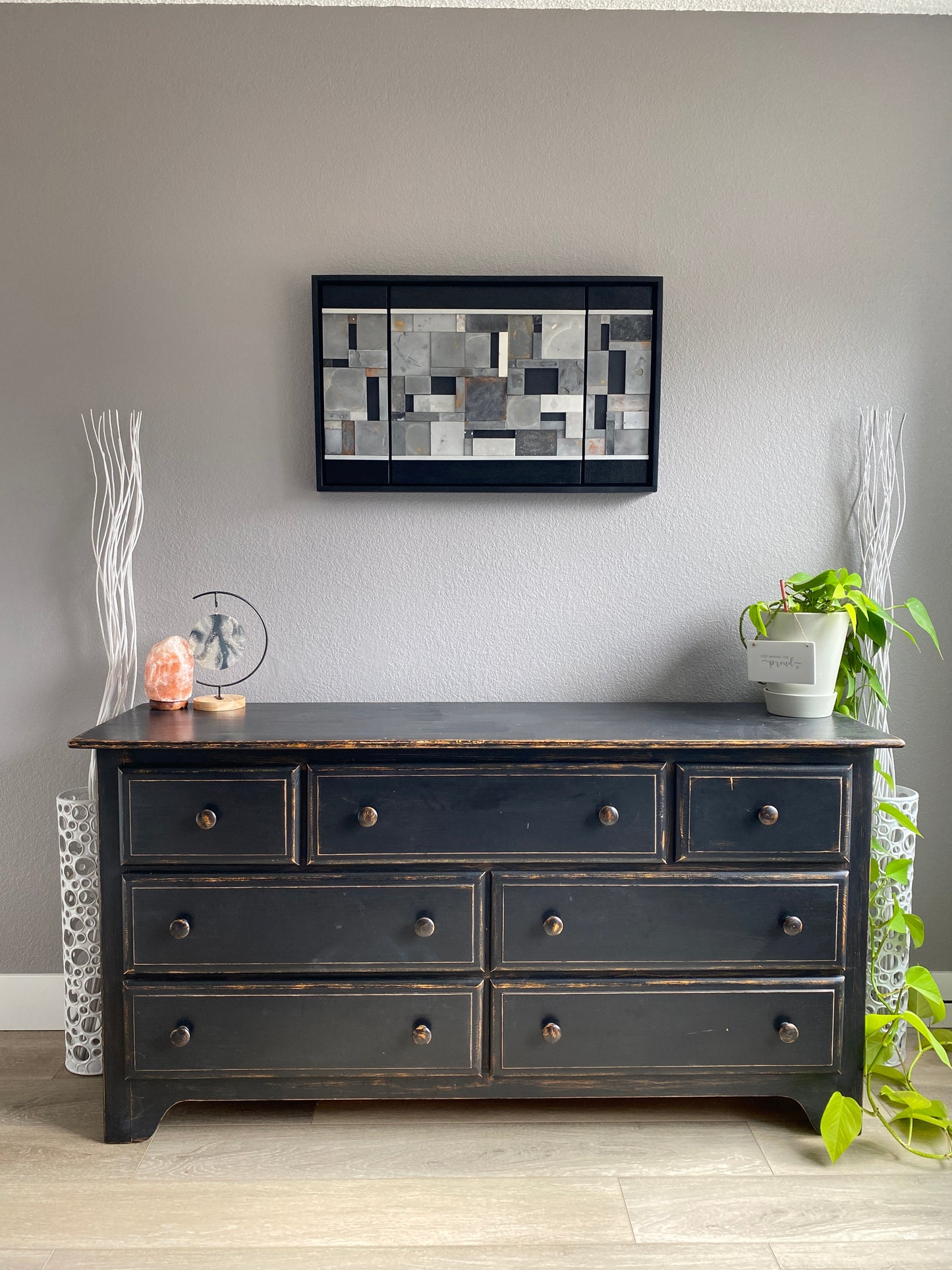 Mosaic triptych wall art on a gray wall, above to a decorative dress.