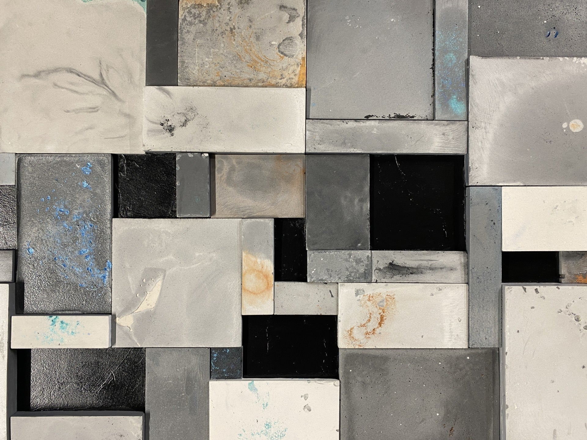 Mosaic pattern of variously shaped and sized metallic tiles in gray, black, and white.