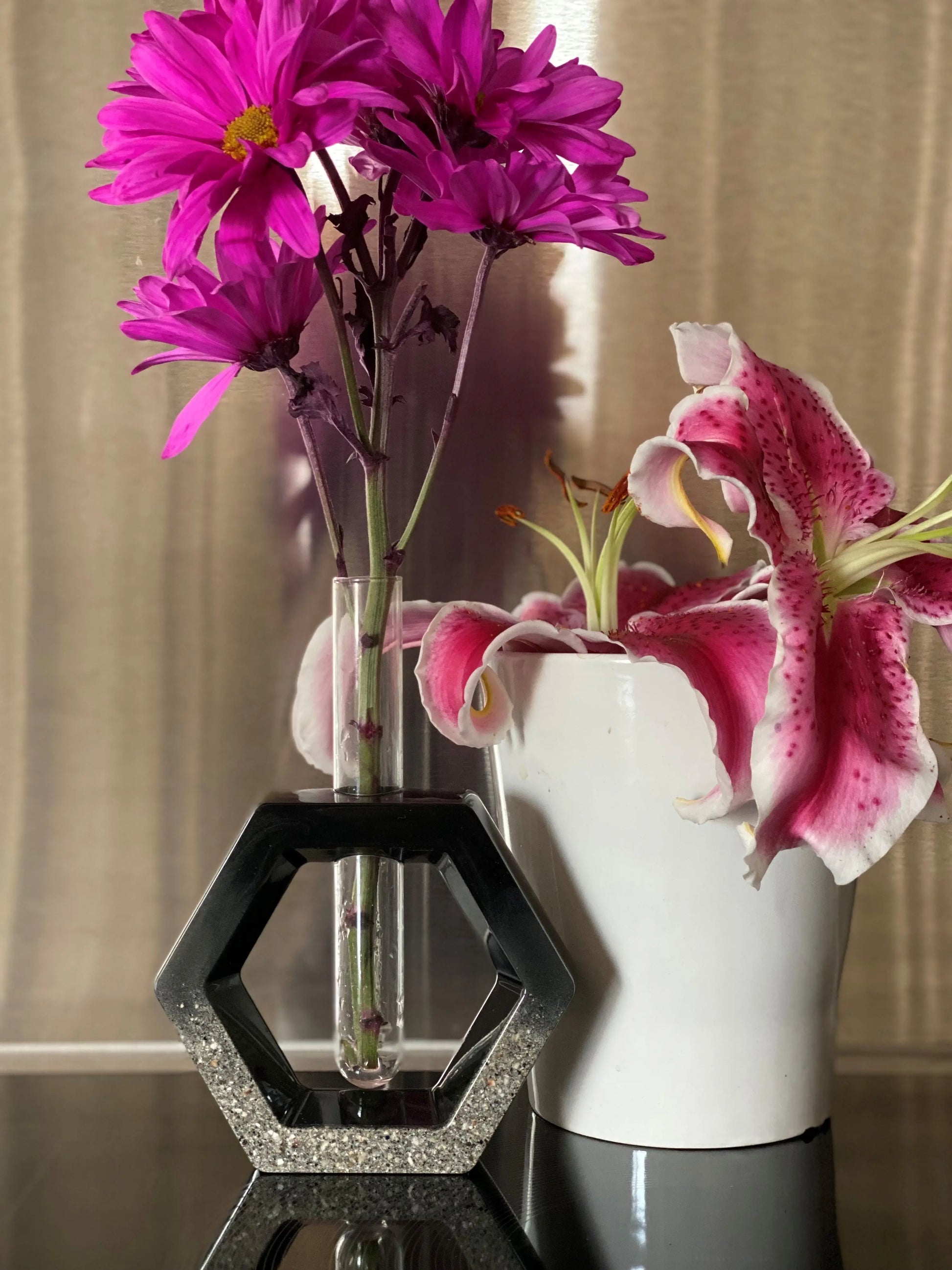 Two vases with pink flowers on a reflective surface