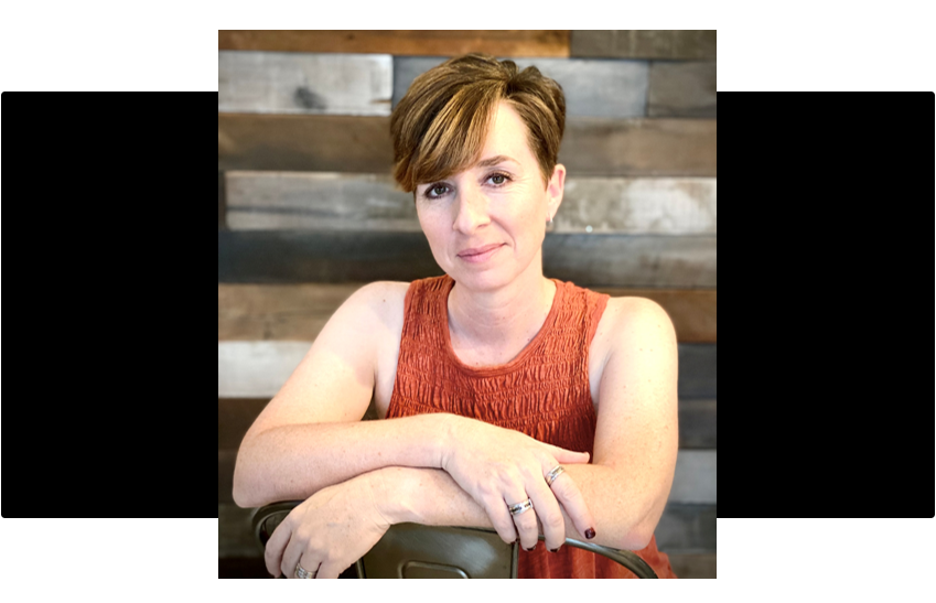 Woman in an orange dress sitting against a wooden panel background