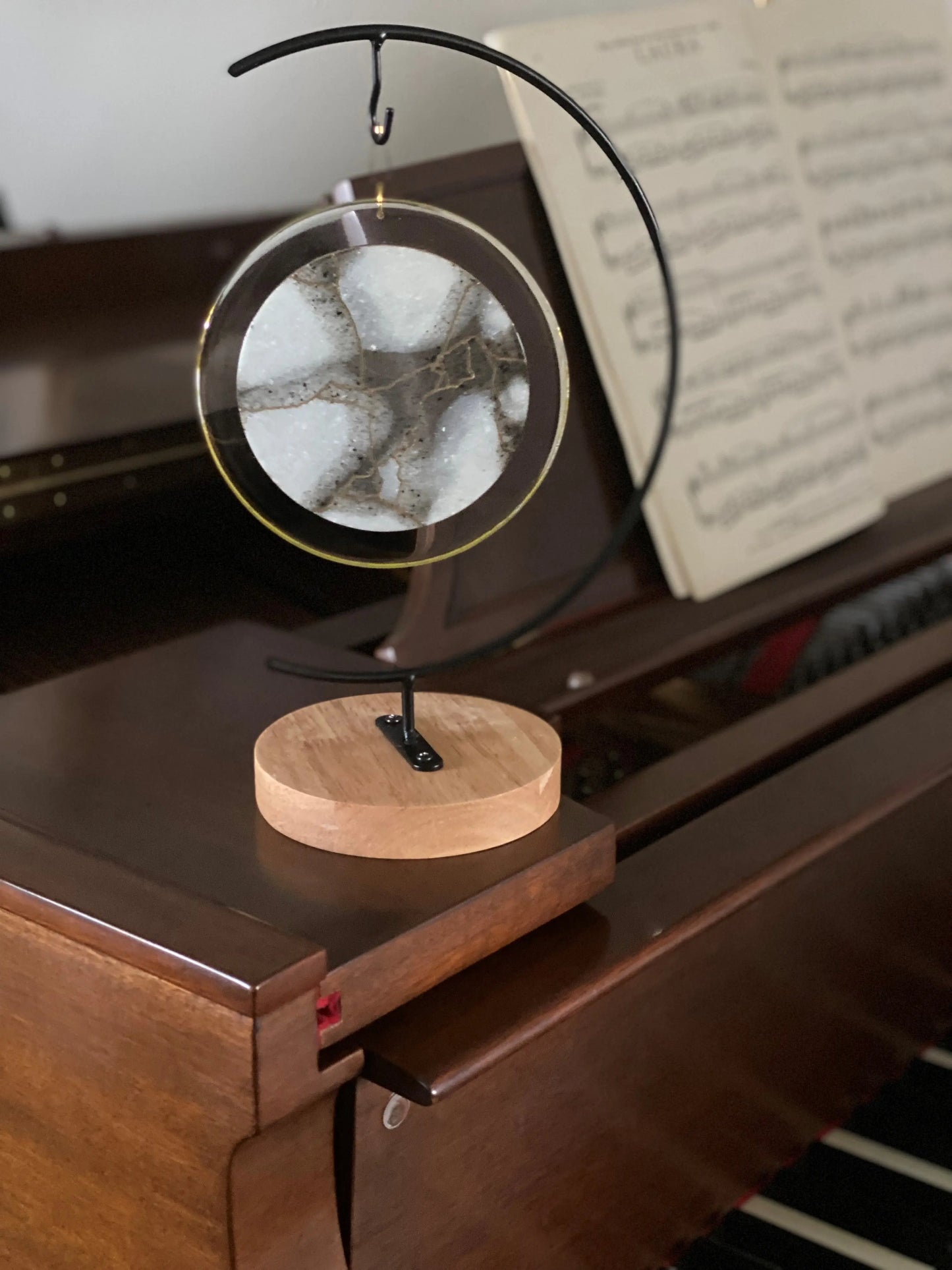 Decorative ash infused stand on a piano with sheet music in the background