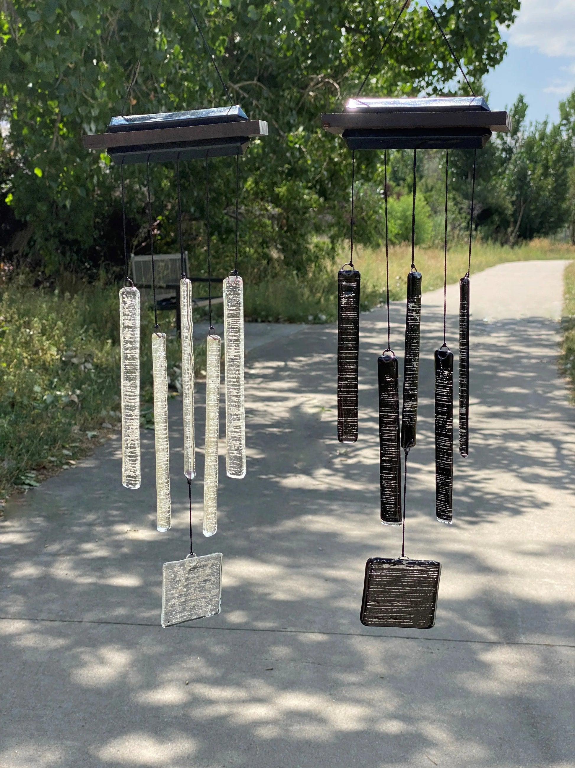 Wind Chimes with infused ash, both black and clear along a path with bench.