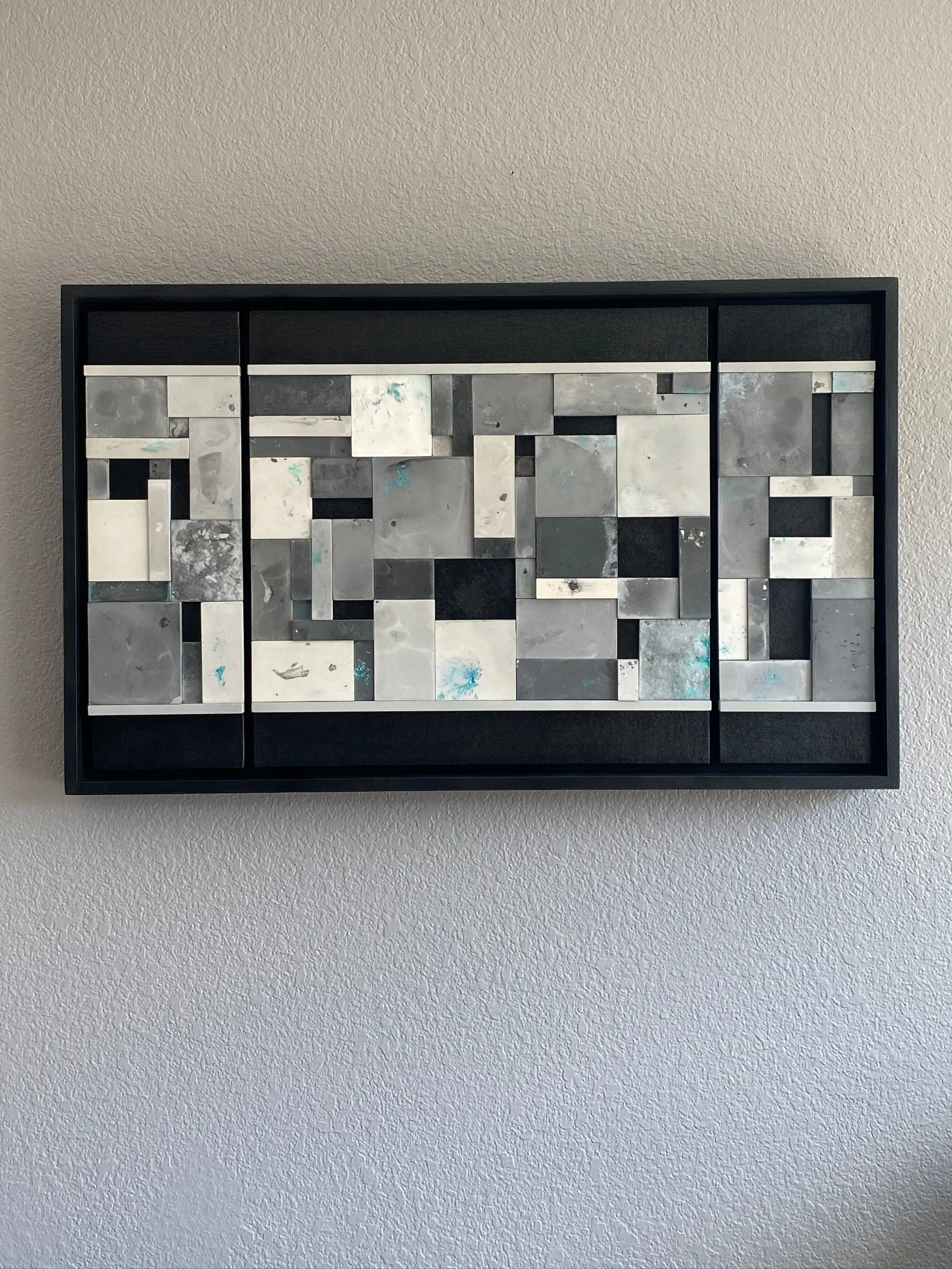 Close-up of Ocean’s Memory showing layered acrylic resin tiles with shimmering mica pigments and textured paint details on grey wall.
