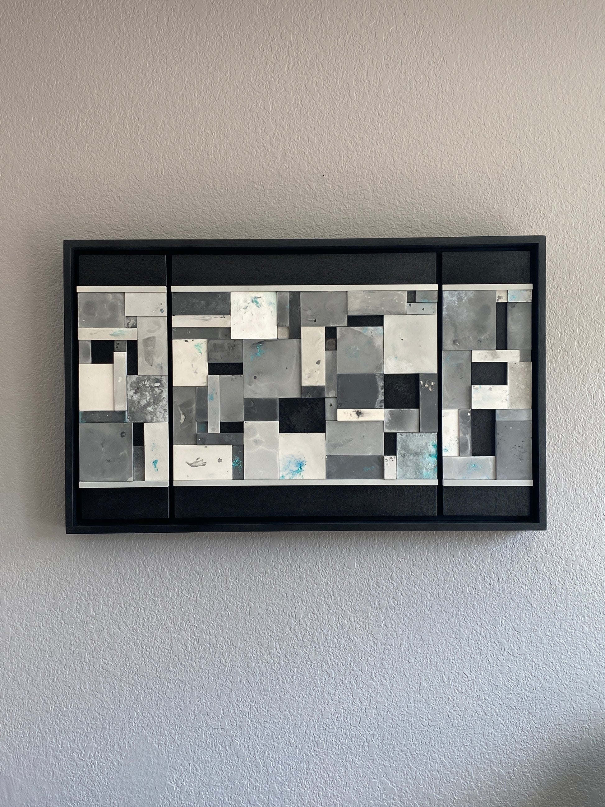 Close-up of Ocean’s Memory showing layered acrylic resin tiles with shimmering mica pigments and textured paint details on grey wall.
