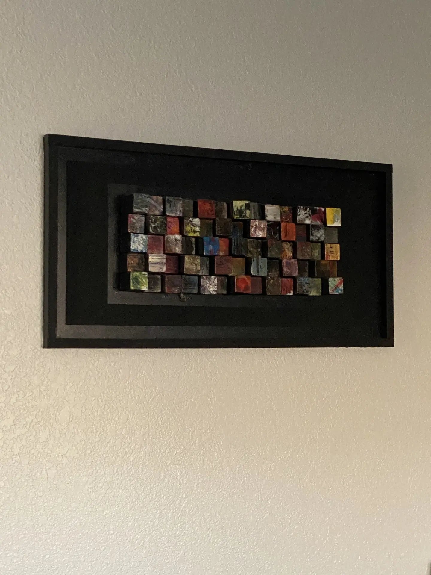 Framed artwork made from painted wooden blocks of varying heights, created collaboratively by Tiffany, Ally, and Kylie.