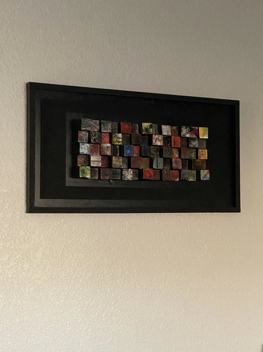 Framed artwork made from painted wooden blocks of varying heights, created collaboratively by Tiffany, Ally, and Kylie.