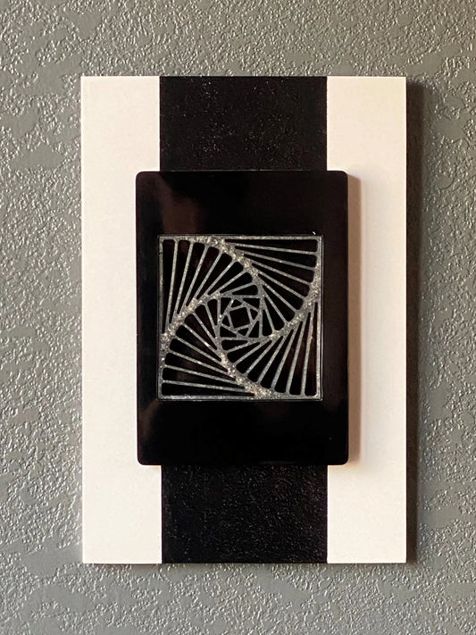 Pinwheel cremation ash memorial wall art with spiraling resin center on white frame and black border