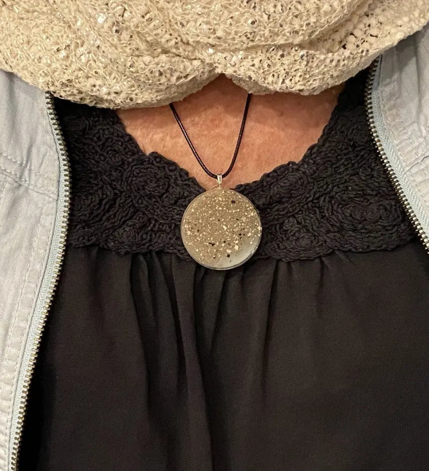 Person wearing a black lace collar with a round pendant necklace.