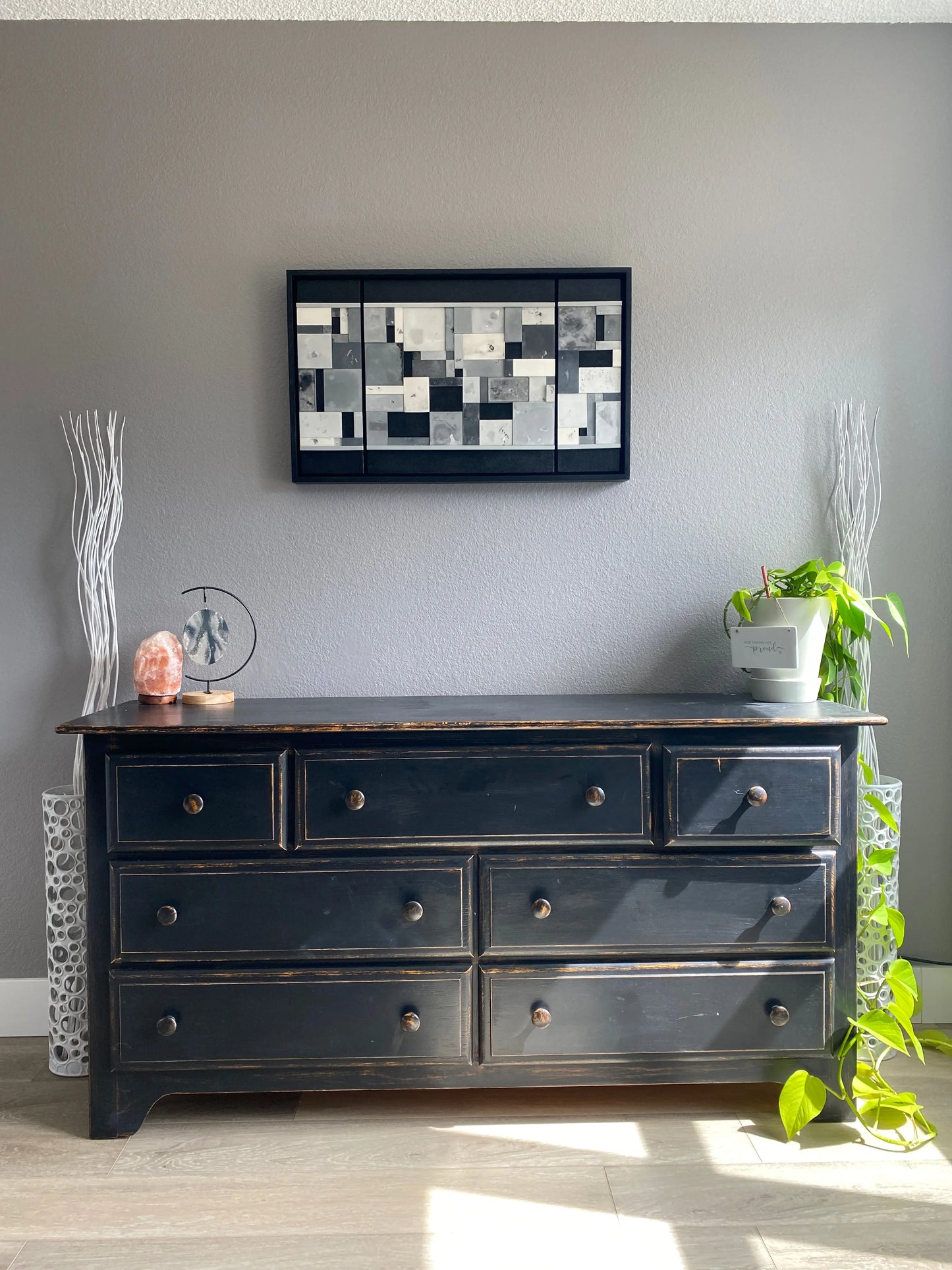 Black dresser  with decorative elements on a gray wall