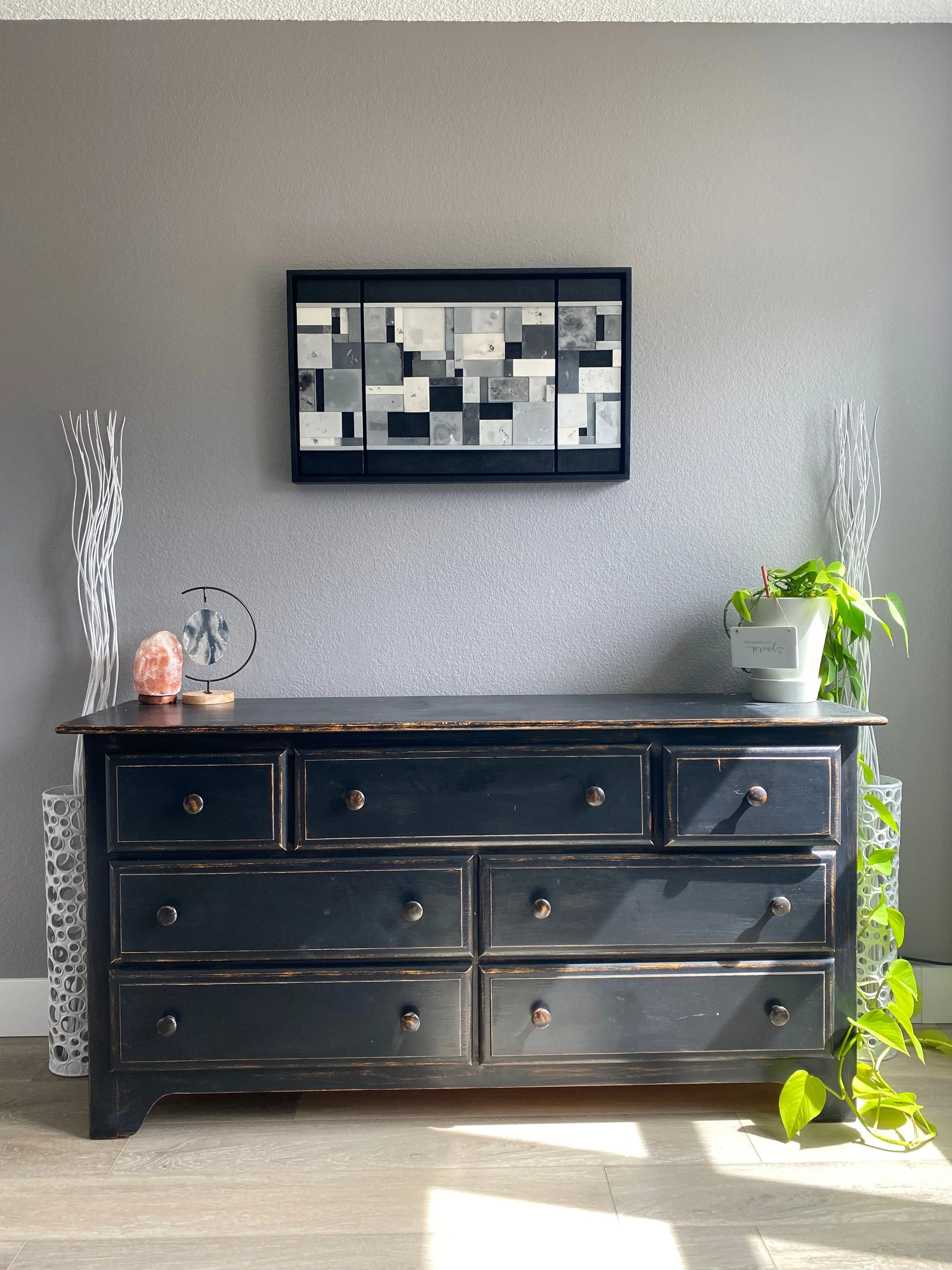Black dresser  with decorative elements on a gray wall