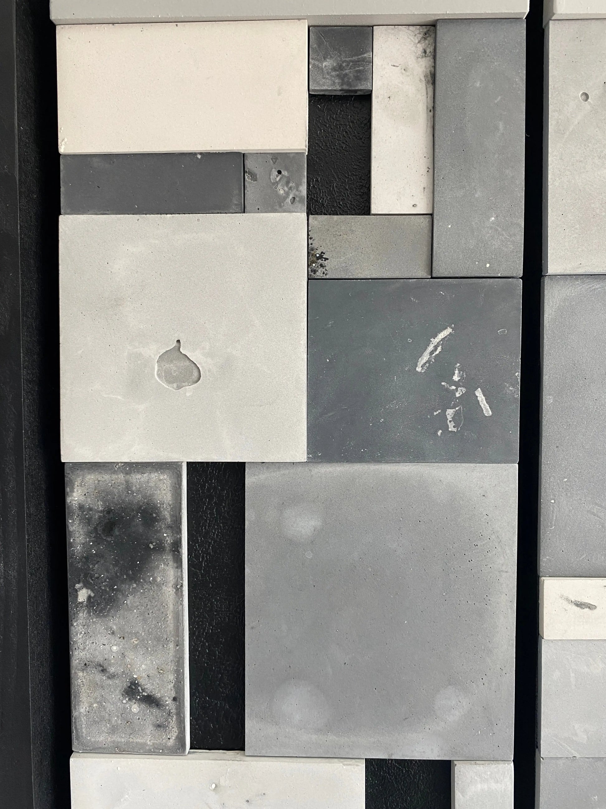 Pattern of gray, black, and white tiles on a wall.