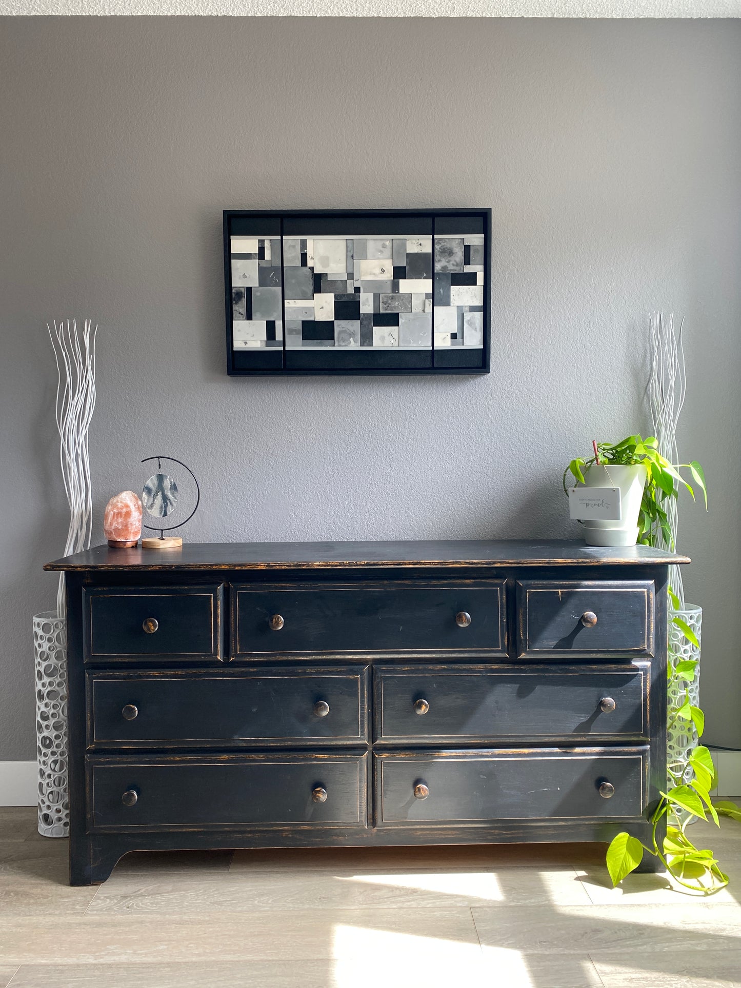 Black dresser  with decorative elements on a gray wall