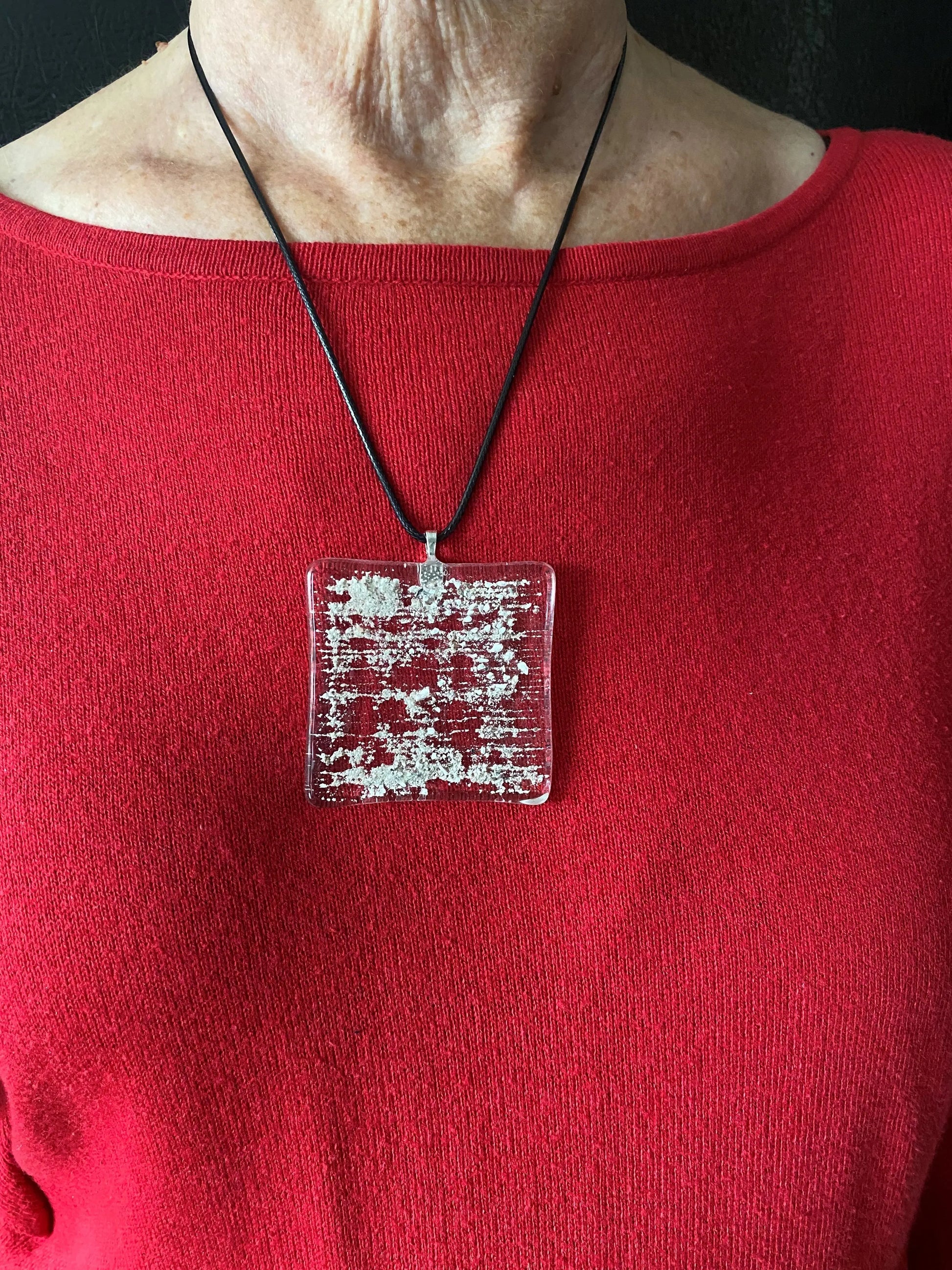 Red garment with a square necklace featuring cremation ash.