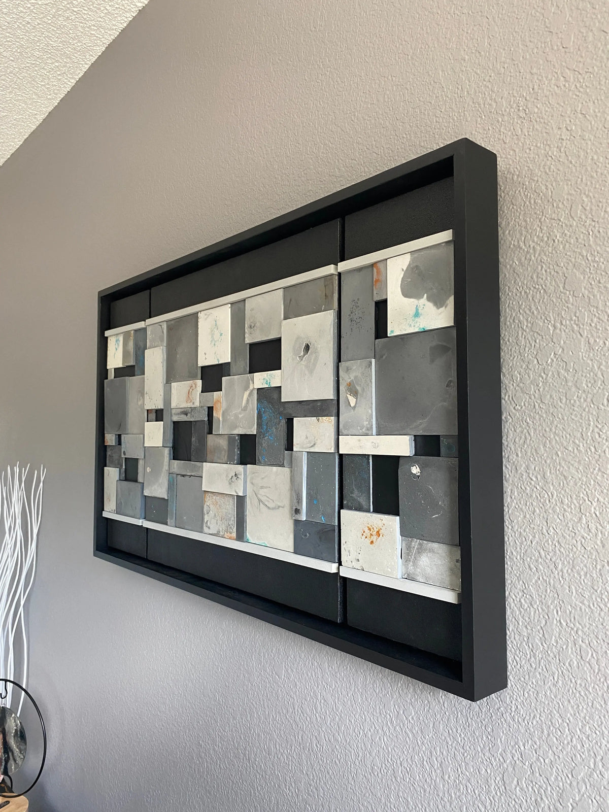Decorative wall mirror with geometric pattern in a black frame on a plain wall.